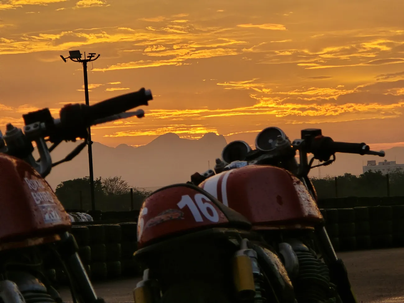 Cafe racers silhouetted at sunrise on a race track